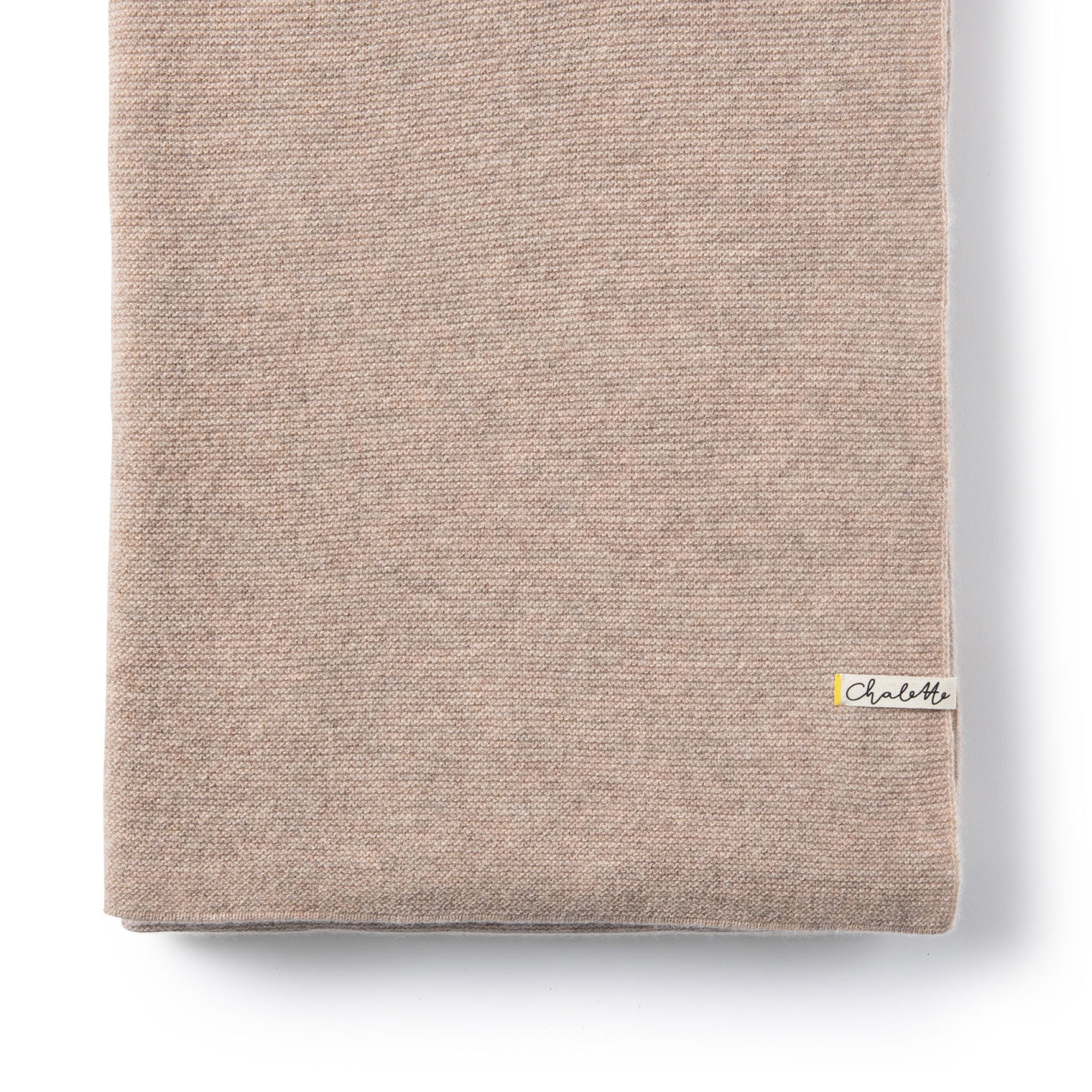 Gefaltete Babydecke in beige auf weißem Hintergrund