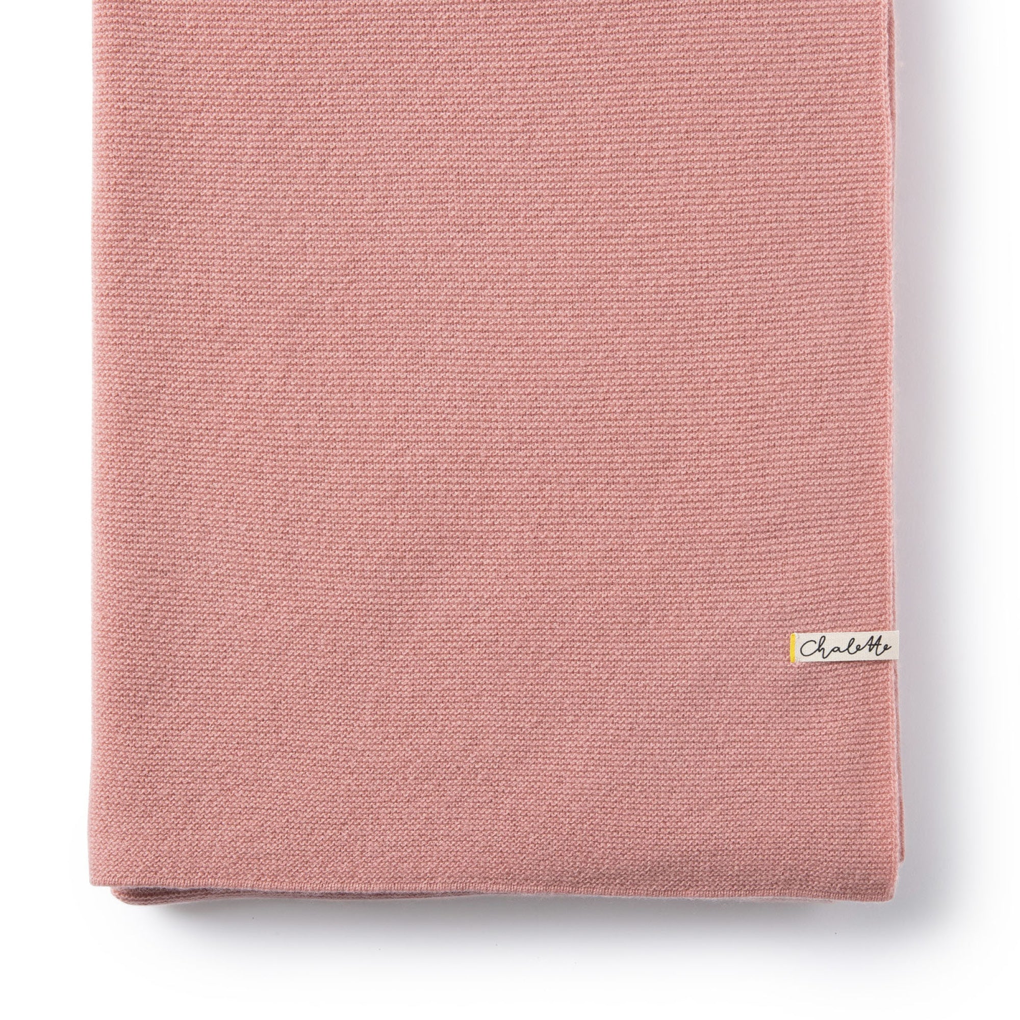 Gefaltete Babydecke in rosa auf weißem Hintergrund