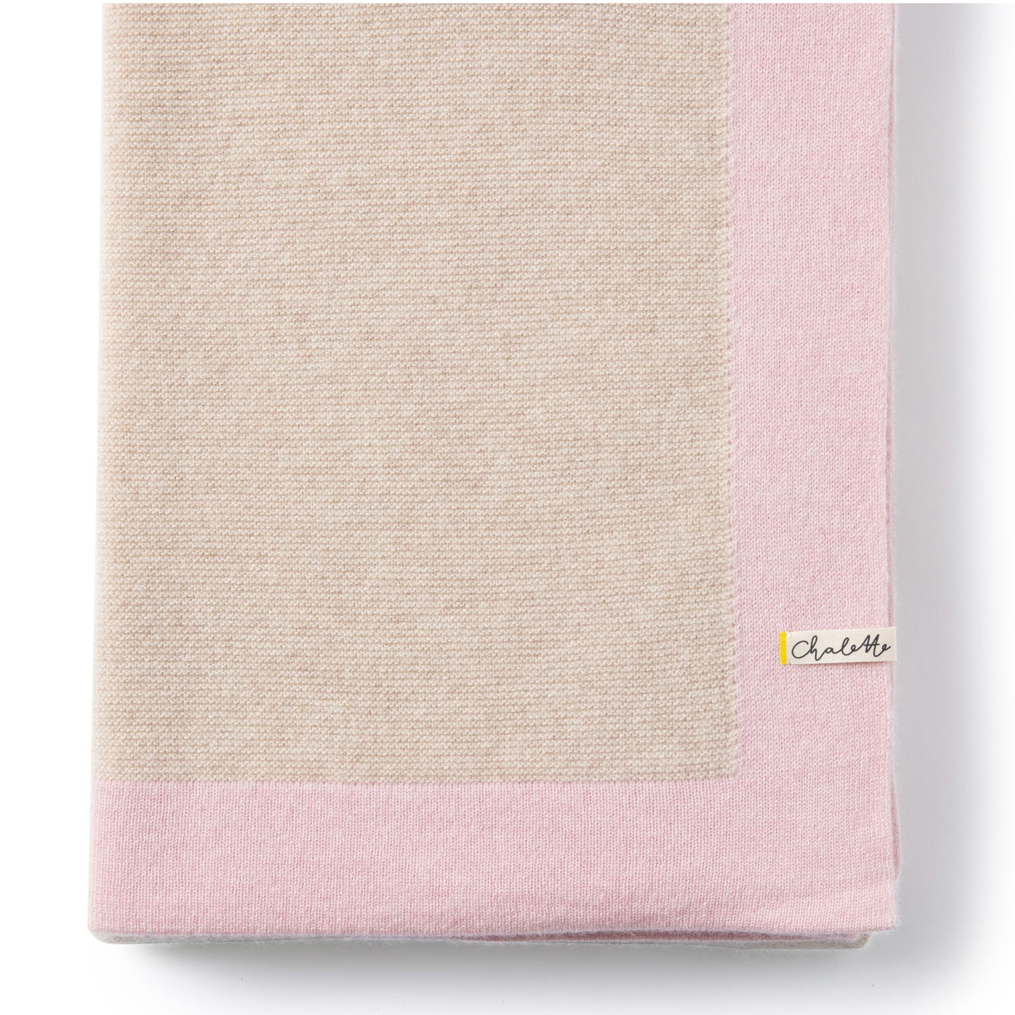 Gefaltete Babydecke in beige mit rosa Rand aus Kaschmir auf weißem Hintergrund