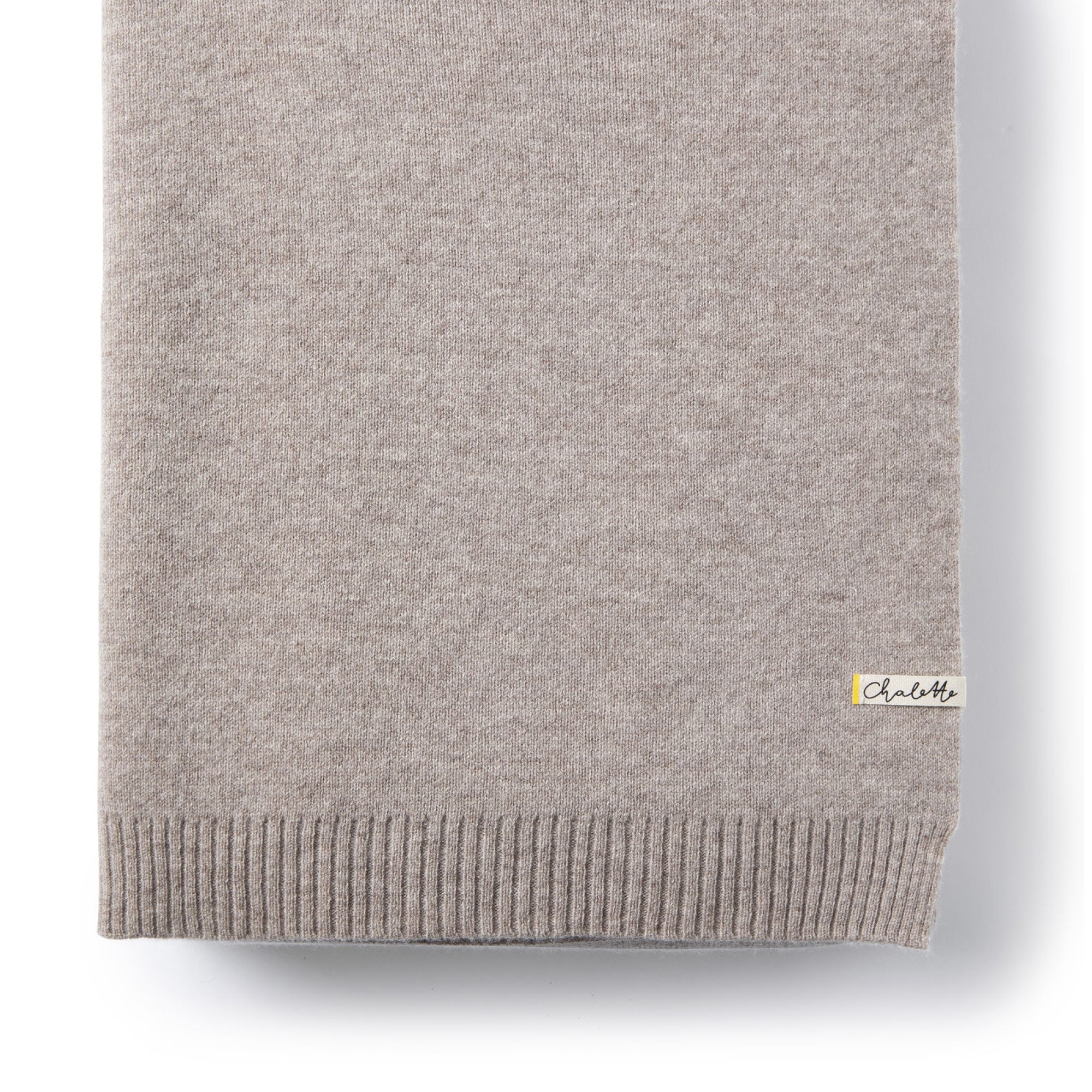 Sofadecke von Chalette in grau liegt gefaltet auf weißem Hintergrund