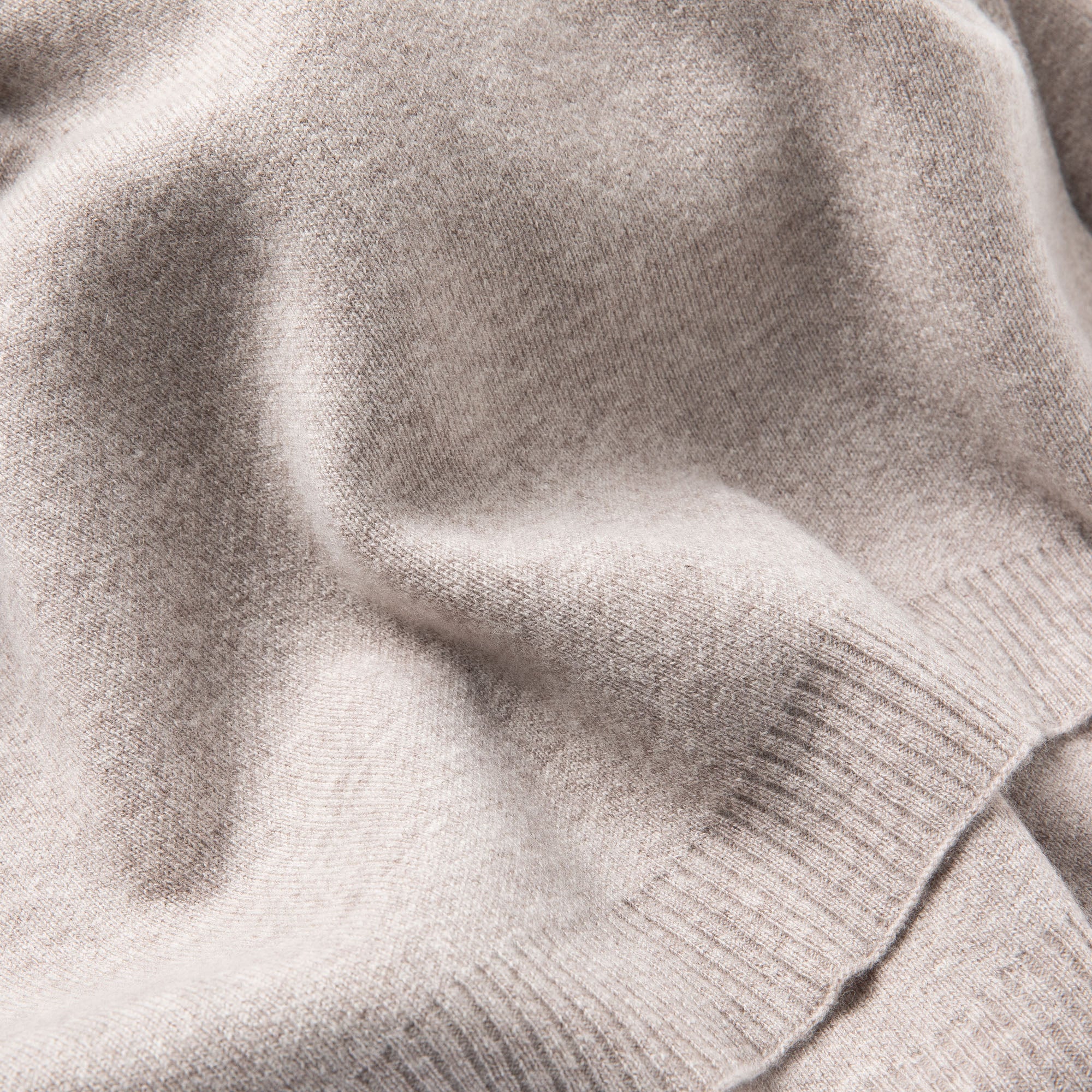 Nahaufnahme einer Sofadecke in grau mit feinem Strickmuster