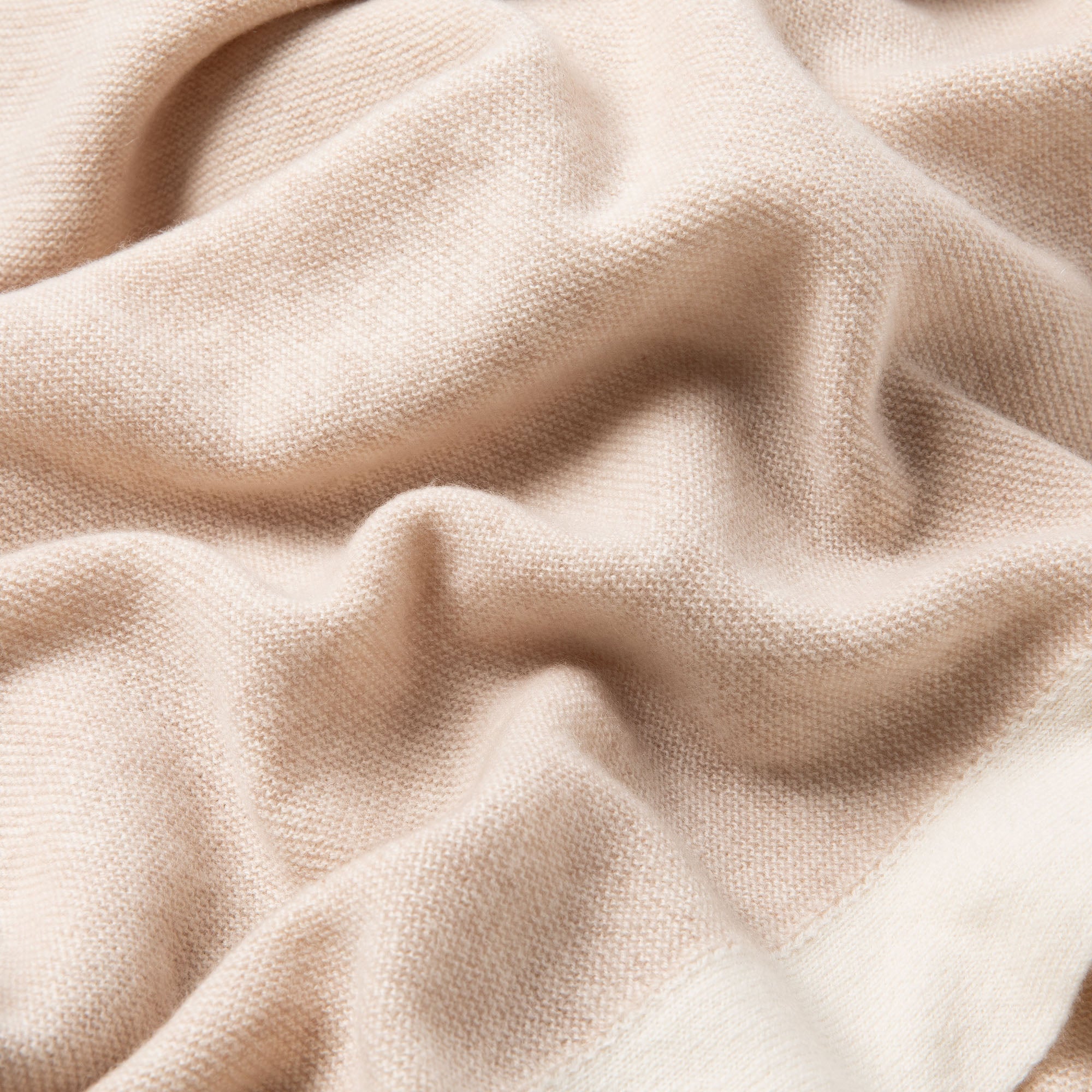 Detailaufnahme einer beigen Babydecke mit Rand in off-white, feines Strickmuster