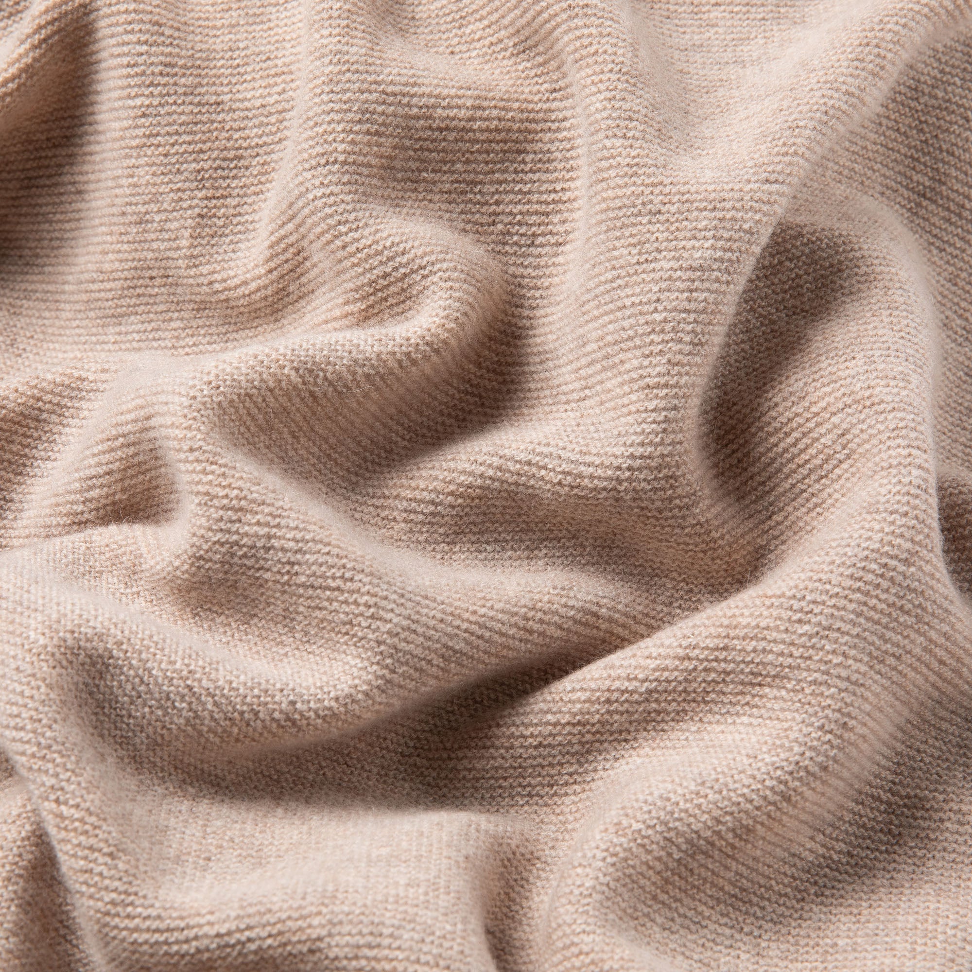 Detailaufnahme einer Babydecke in beige, weich drapiert mit sichtbarer Struktur