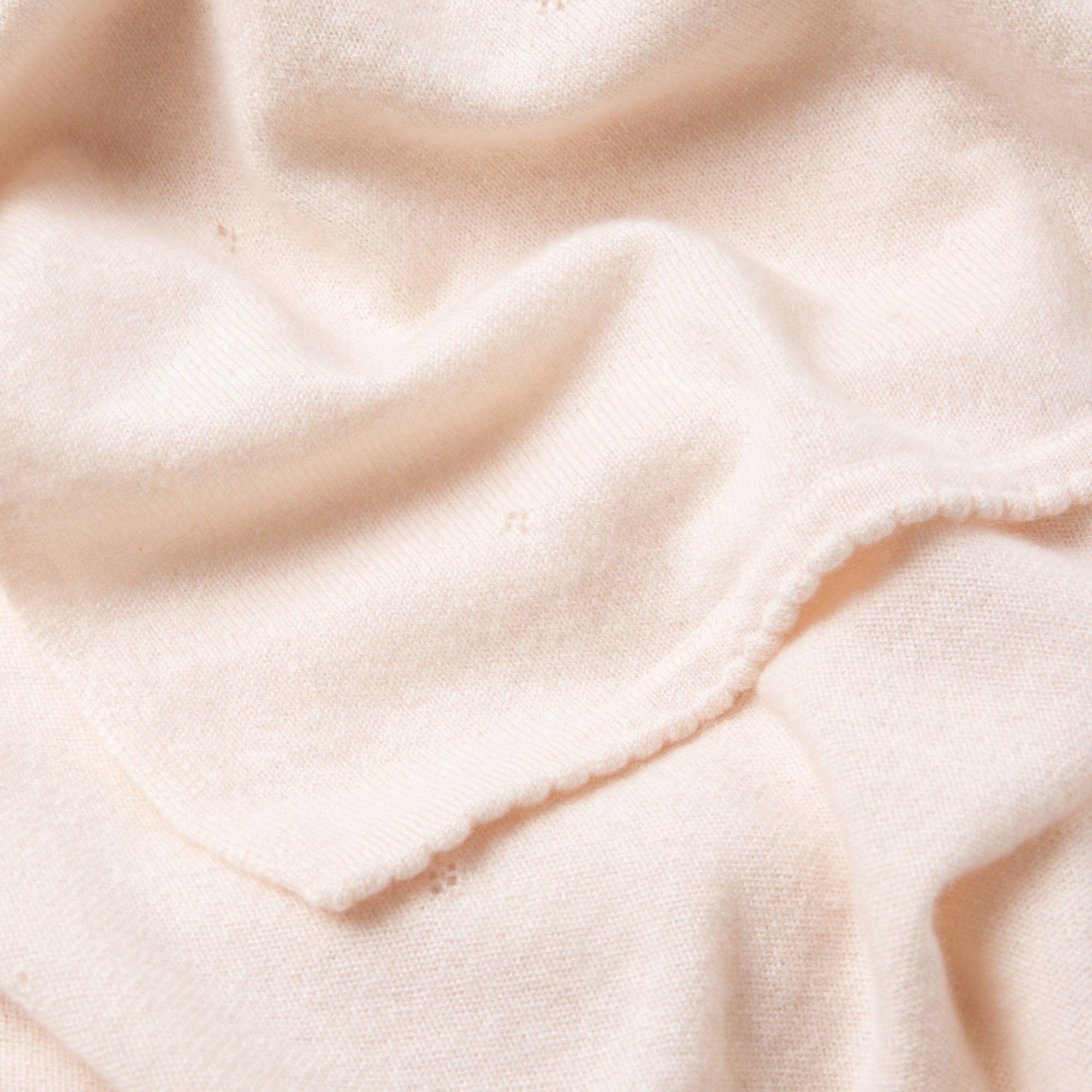 Detailaufnahme einer Kaschmirdecke in off-white mit Lochmuster und verziertem Rand