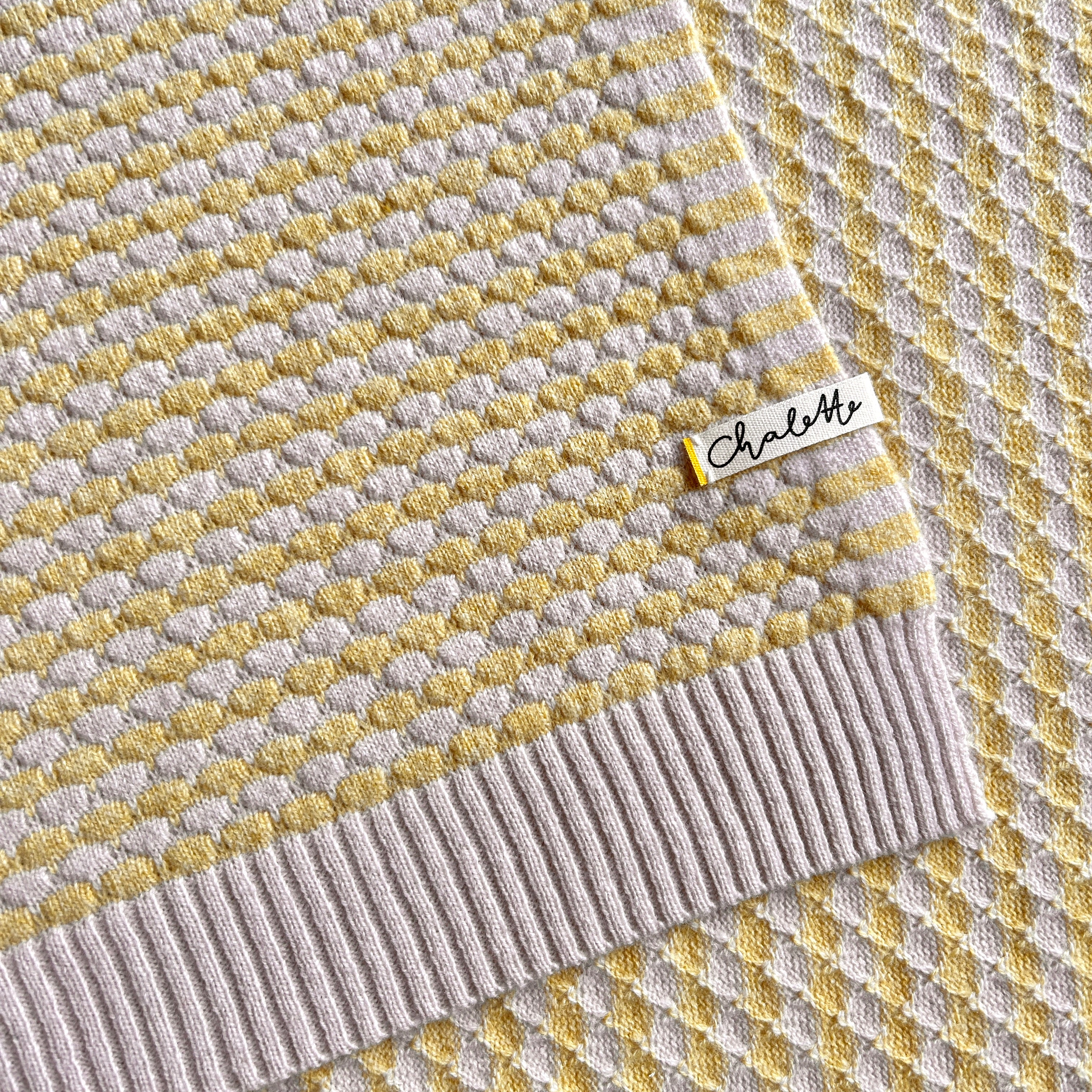 Nachaufnahmen einer Babydecke in Beige und Gelb.