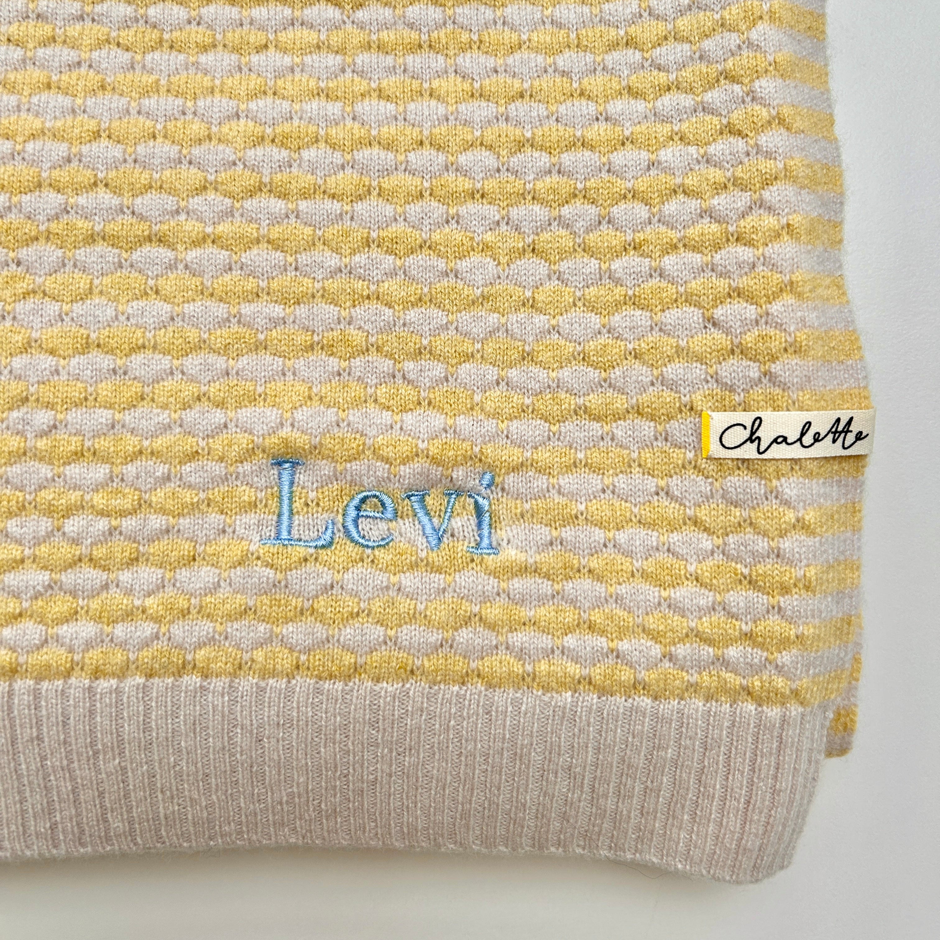 Babydecke in Beige und Gelb. Bestickt mit Name "Levi" in Blau.