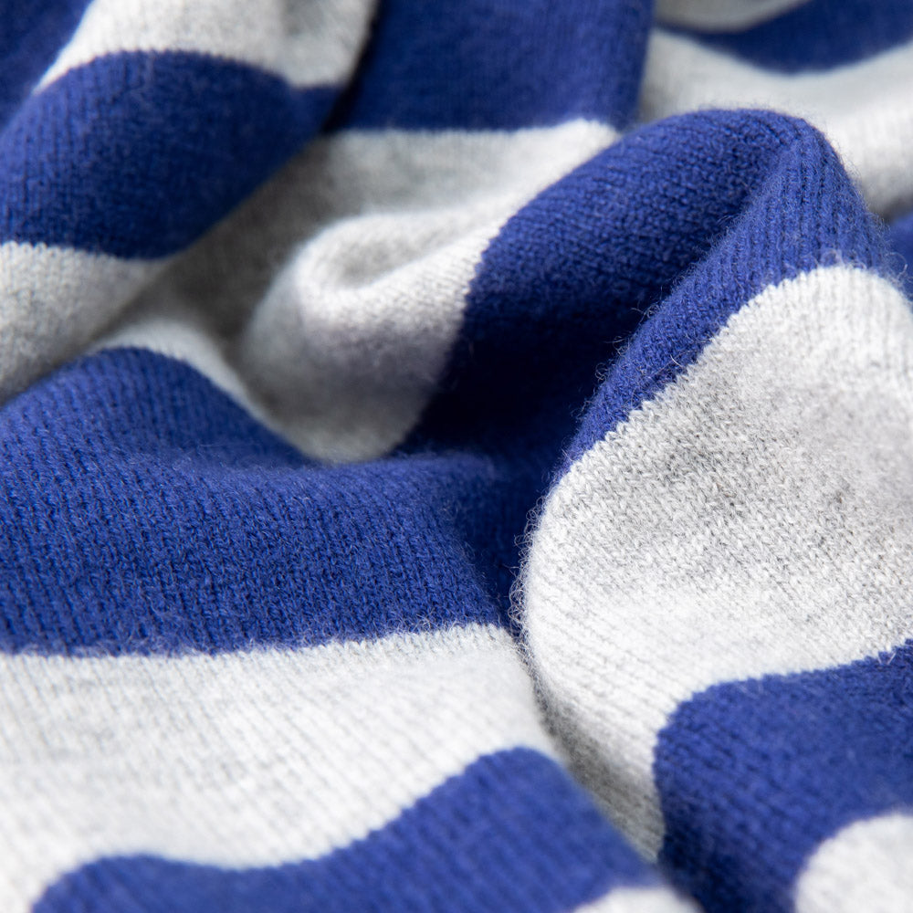 Detailaufnahme einer Babydecke in blau und grau gestreift, weich drapiert mit sichtbarer Struktur