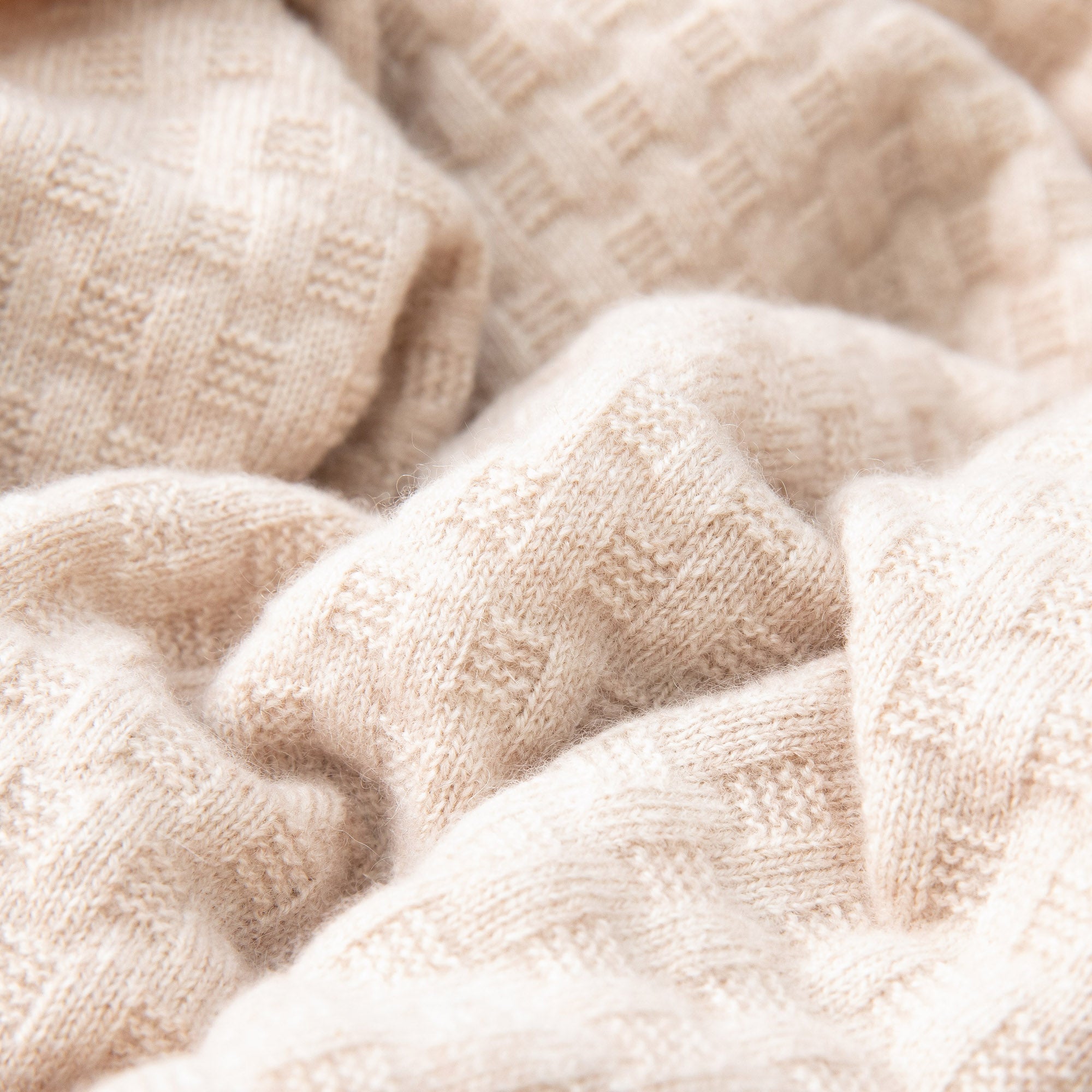 Detailaufnahme einer Babydecke in Beige mit Waffelstruktur, weich drapiert mit sichtbarer Struktur