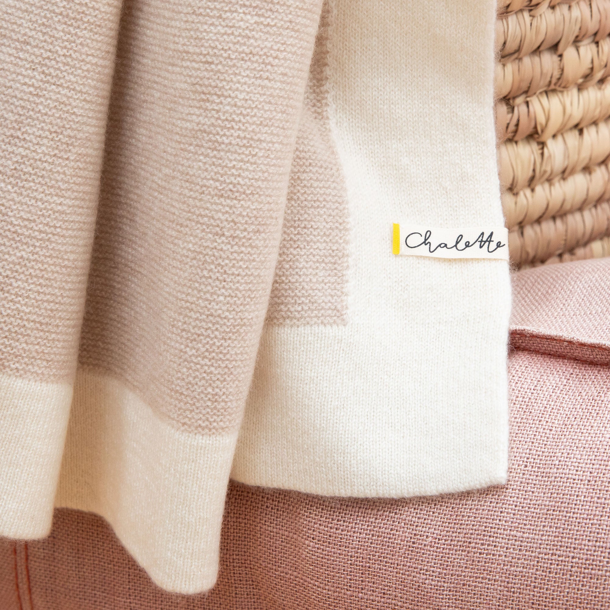 Detailaufnahme einer beigen Kaschmirdecke mit Rand in off-white mit feinem Strickmuster, sichtbares Etikett: Chalette