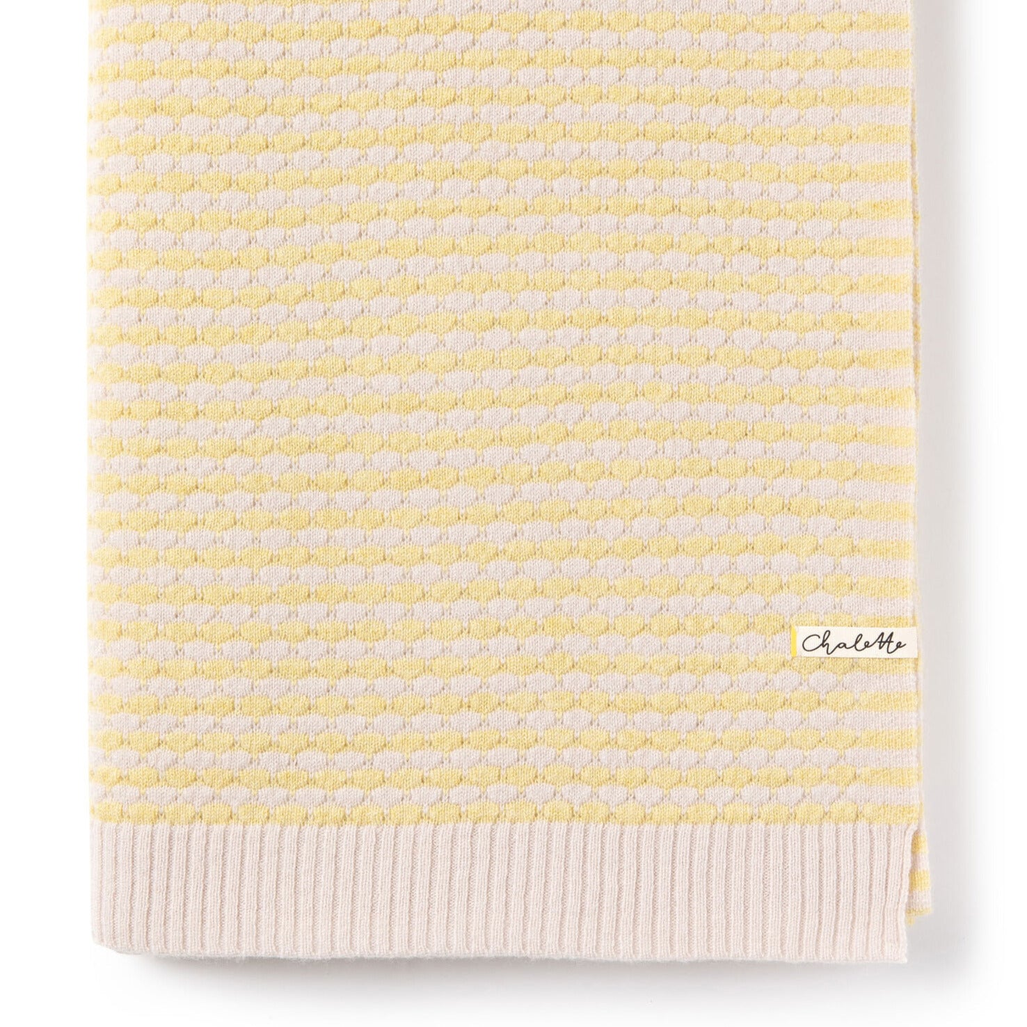 Gefaltete Babydecke mit strukturiertem Wabenmuster in Gelb und Beige, mit Chalette-Etikett