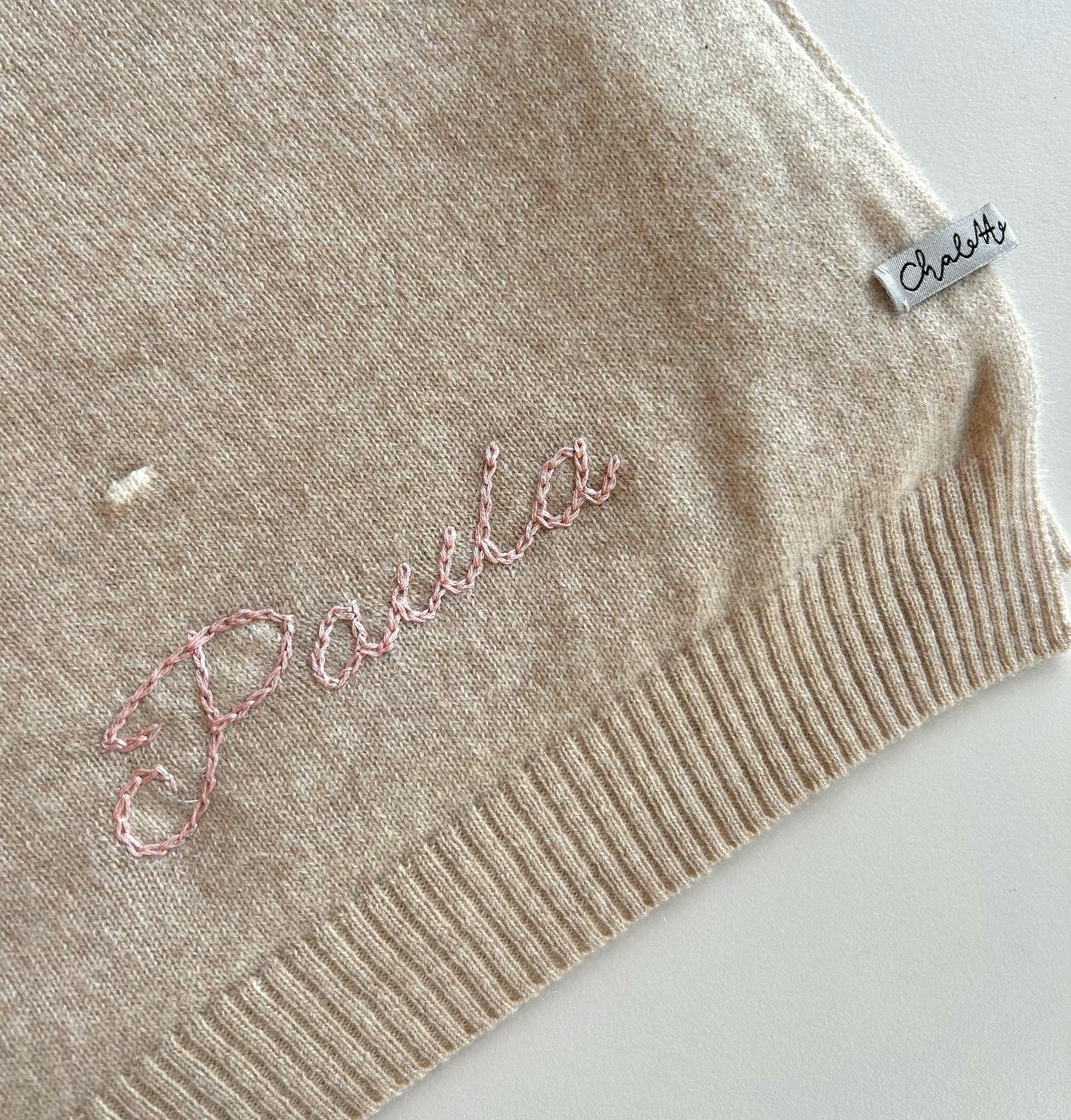 Kaschmirdecke in Beige mit Punkten in Off-White. Bestickt mit Name "Paula" mit Handstickerei in Rosa.