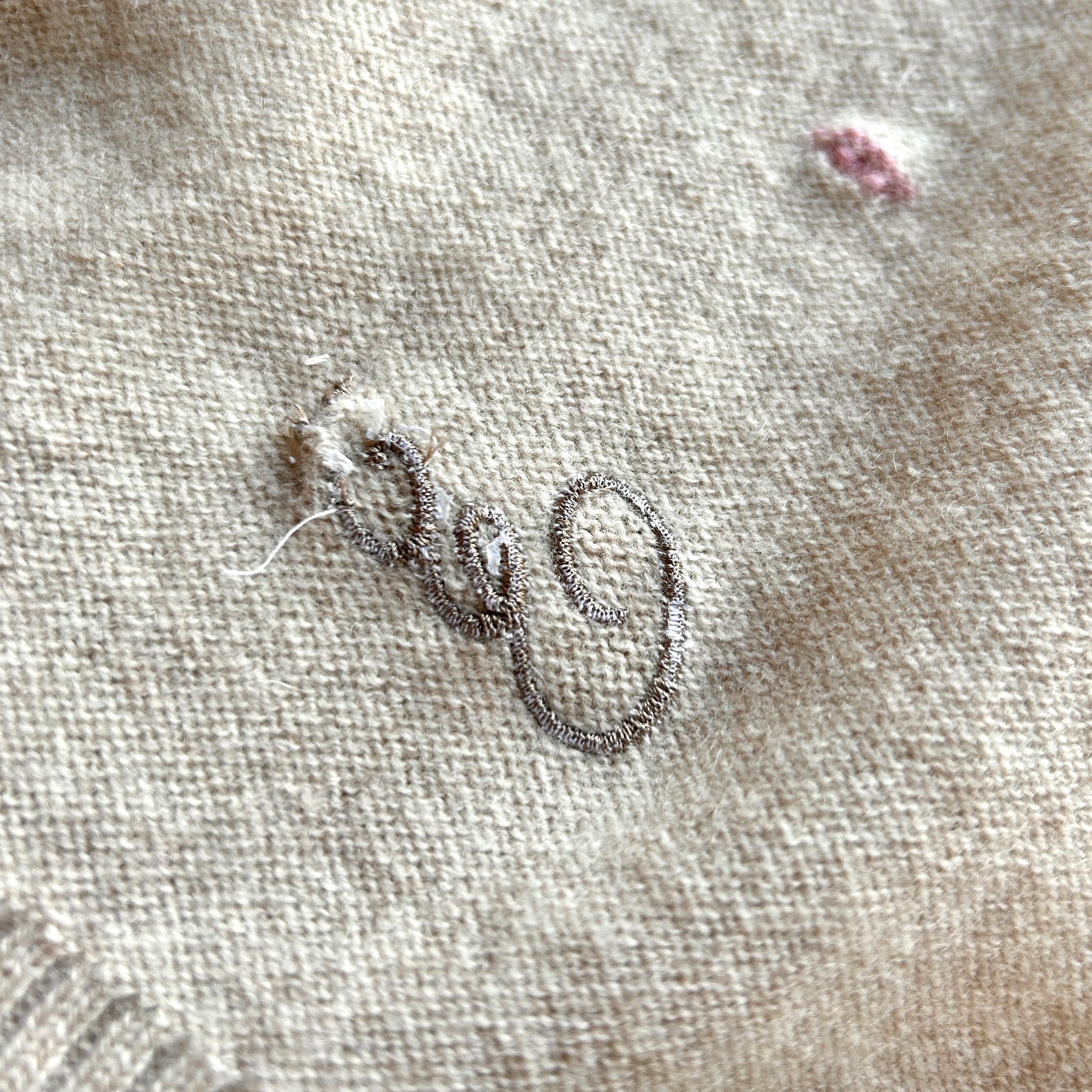 Rückseite einer Babydecke in Beige. Stickerei hat einen Stickfehler, Fäden sind am Ende zusammengezogen