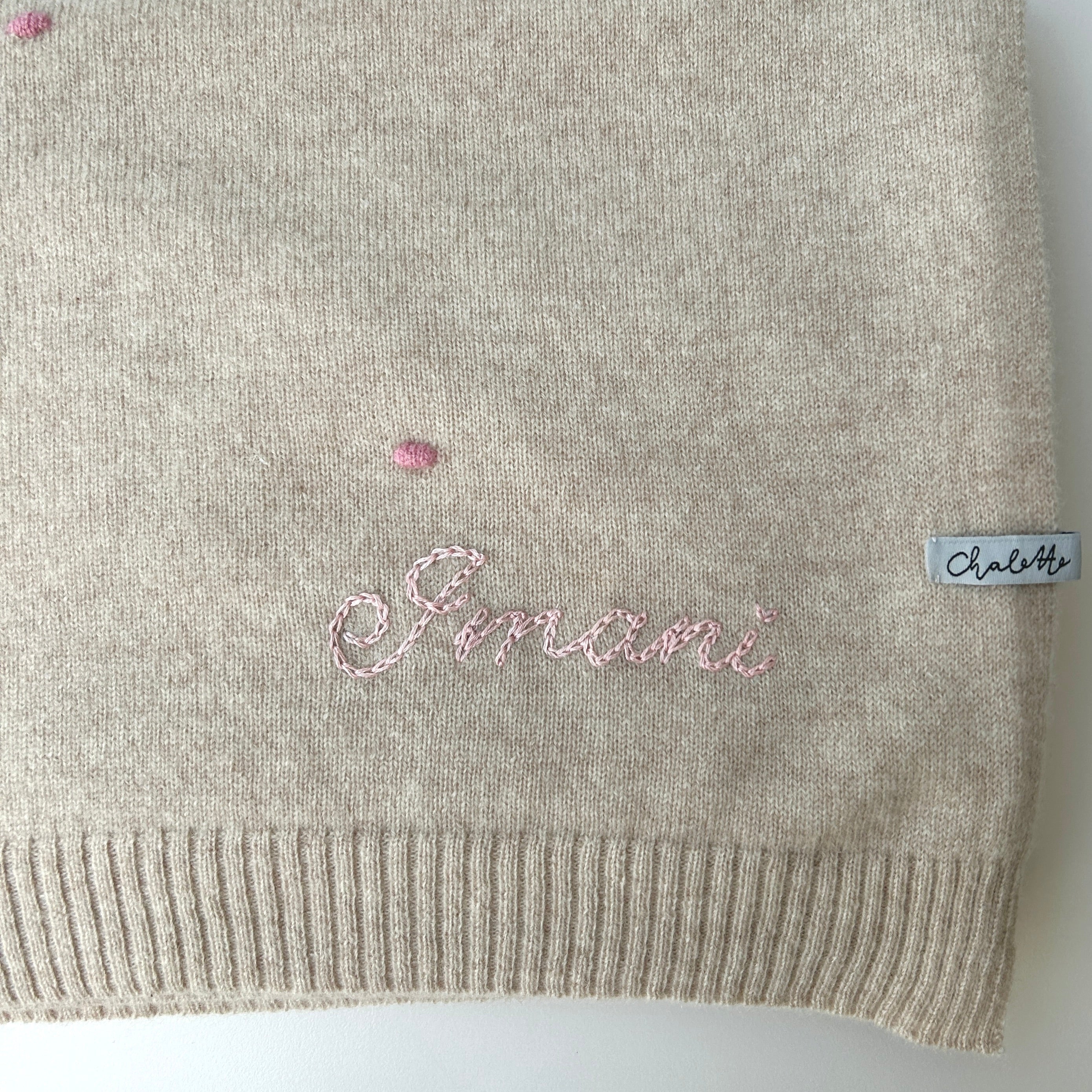 Kaschmirdecke in Beige mit Punkten in Rosa. Bestickt mit Name "Imani" mit Handstickerei in Hellrosa.